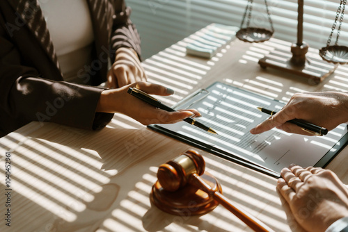 Lawyer is pointing with a pen where to sign a legal document during a meeting in the office