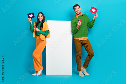 Full length photo of two people blogger board use device receive like network ecommerce post isolated on blue color background