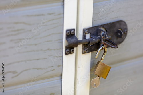 Close-up of Secure Padlock and Key on Metal Door Lock Mechanism, Emphasizing Security and Protection Concept in Outdoor Urban Setting