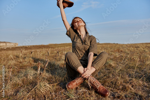 Woman enjoying freedom outdoors with hands in air holding hat in travel fashion beauty concept