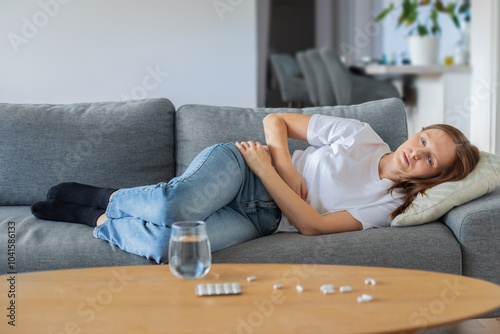 Young woman lying on sofa and suffering from abdominal pain at home