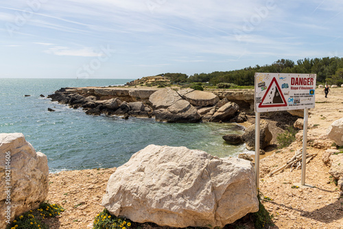 Danger sign falling rocks at rough rocky coastline of Martigues in Alpes-Cote d'Azur region in France