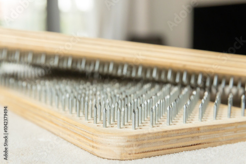  Side view of a wooden acupressure sadhu board, highlighting its rows of sharp metal spikes intended for therapeutic use.