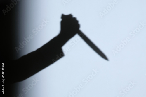 Male hand shadow holding with kitchen knife on the wall in home to night.