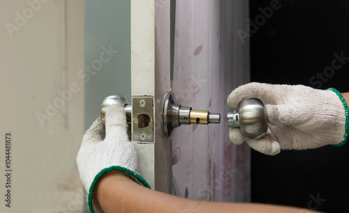 Locksmith on wood door with screwdriver for repair or fix silver knob.