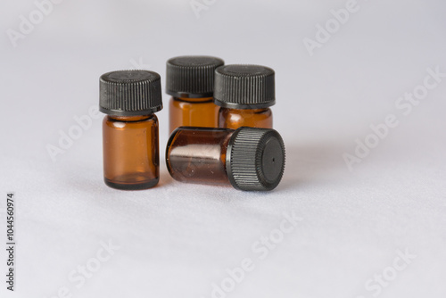 Small amber glass bottles with black caps on a white surface, perfect for essential oils or laboratory samples.