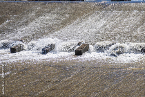 row of chute dentate blocks in concrete water spillway channel slope slowing down the flow of water running down.