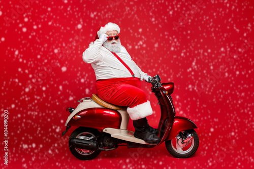 Profile side view portrait of nice bearded confused amazed funny funky Santa riding moped hurry up cool winter season discount shopping mall isolated on bright vivid shine vibrant red color background