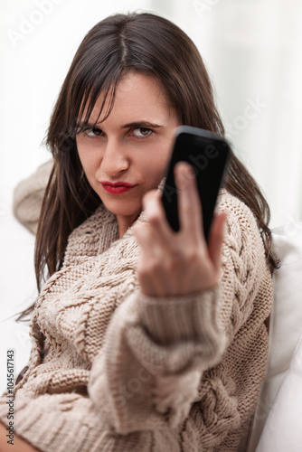 Woman stares angrily at phone, contemplating revenge