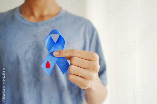 Hand holding blue ribbons with blood , world diabetes day