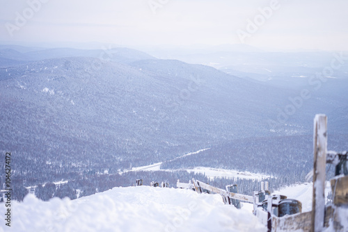 wooded snowy hills, wooden fence in foreground