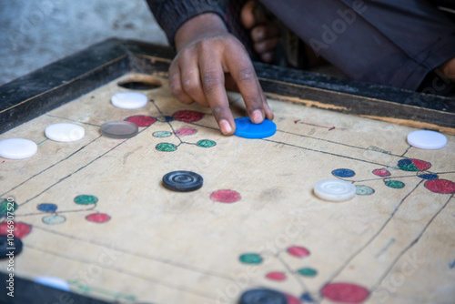 Close-up hand getting ready to hit carrom coins on carrom board