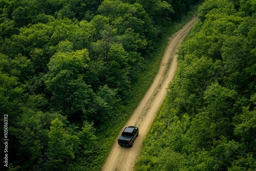 A black pickup truck maneuvers skillfully along a winding, bumpy dirt road, embraced by vibrant, lush greenery all around, culminating in a truly adventurous and picturesque scene before our eyes