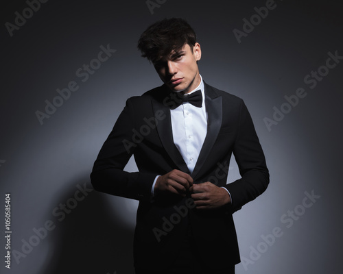 confident businessman unbuttoning elegant black tuxedo