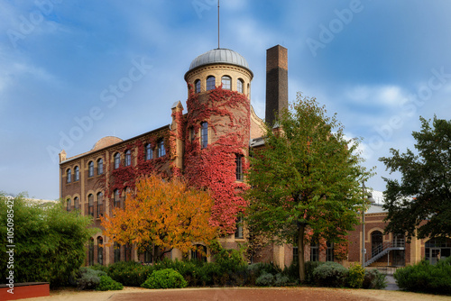 the beautifully restored tower house of the former Vulkan lighting factory from 1909 in Cologne Ehrenfeld with autumnal colors of the tasteful plantings