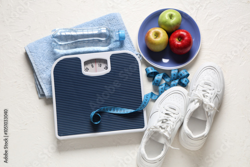 Scales with measuring tape, sneakers and apples on white grunge background. Weight loss concept