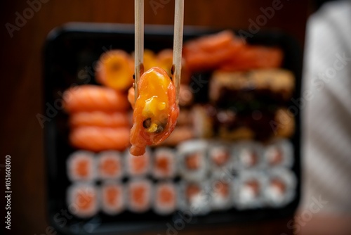 Sushi held by chopsticks over a platter.