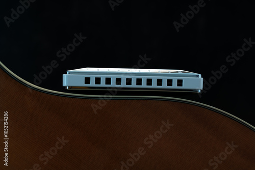 Macro close up diatonic harmonica lying on side of guitar body showing the curve of the guitar body