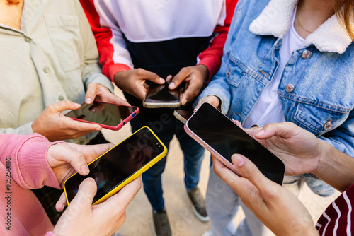 Close up of teen group of friends using mobile phones together outdoor, sharing content on social media networks or chatting online. Tech and youth lifestyle concept