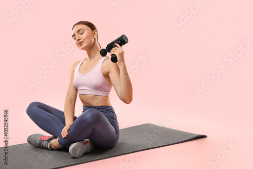 Woman using percussive massager to relieve trapezius muscle on pink background. Space for text