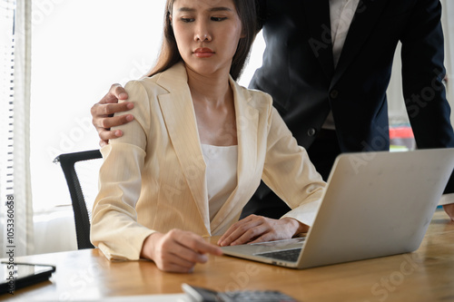 A male colleague or supervisor places a hand on the shoulder of an uncomfortable-looking female employee. Concept issues of sexual harassment, inappropriate behavior, and workplace dynamics.