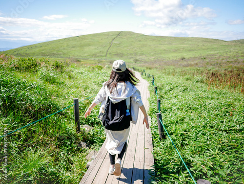 眺めの良い山を楽しそうにハイキングをする女性の後ろ姿