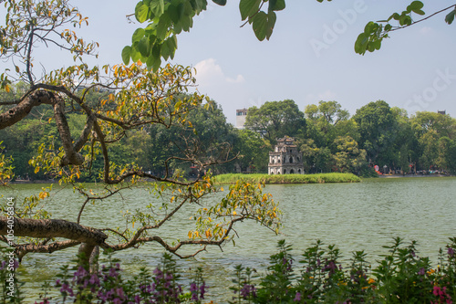 Hanoi, Vietnam, 11-06-2024: branches and view of Turtle Tower (Thap Rua), a small tower built in 1886 in the middle of Sword Lake (Hoan Kiem Lake), dedicated to the hero Le Loi, one of the city symbol