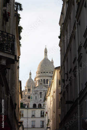 Street view of sacre coeur basilica in Montmartre in Paris in-between buildings in the sun