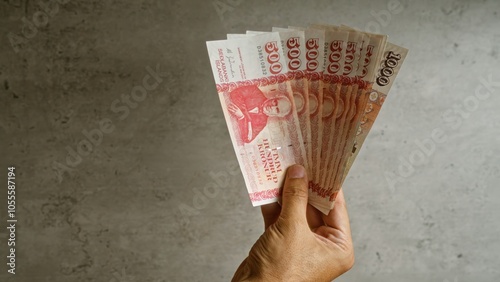 Hand holding a fan of icelandic krona bills against a concrete background, emphasizing financial and economic concepts related to iceland's currency.