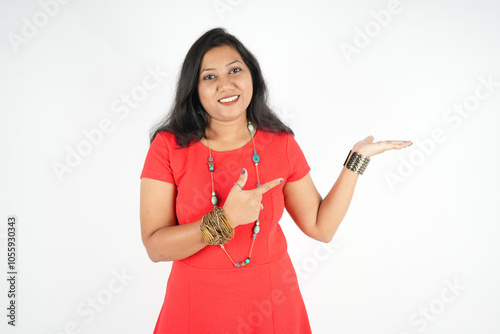 gestural photo cute girl showing open palm pointing side left view, red dress with short sleeve isolated over white background.