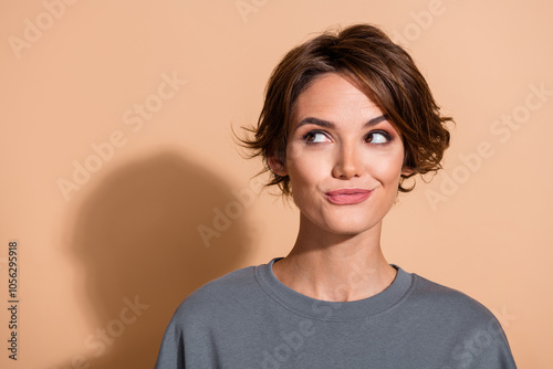 Photo portrait of lovely young lady look tricky curious empty space wear trendy gray garment isolated on beige color background