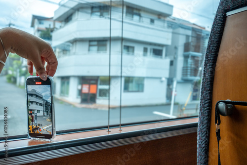 Tourist taking pictures of japanese buildings from a train window using a smartphone