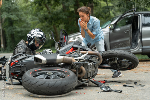 Collision between motorcycle and car on the road. Girl driver hit motorcyclist. Broken and wrecked motorcycle on road