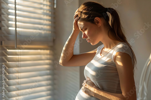 Young pregnant woman experiencing a headache in her home seen from the side.