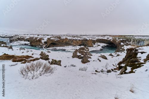 Bridge crossing turquoise river in snow covered icelandic landscape