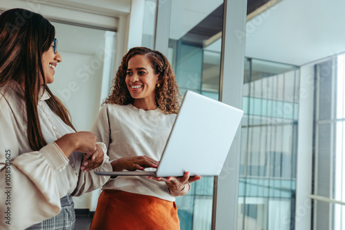 Female team collaborating in modern office while discussing ideas with laptop in hand