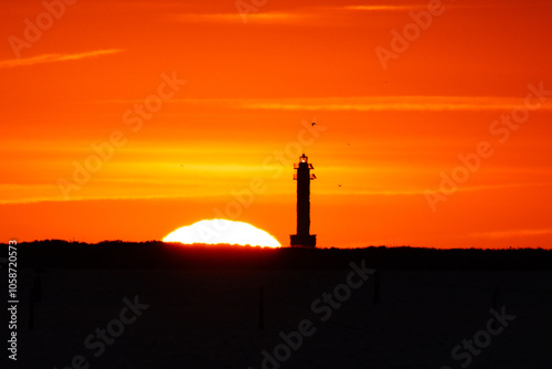 Sol saliente detrás de un faro