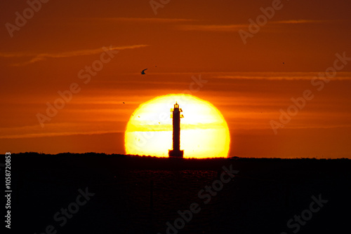 Sol saliente detrás de un faro