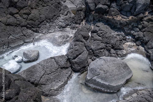 black volcanic rocks with salt residues due to evaporation of sea water, salt and saltpetre on black lava rocks