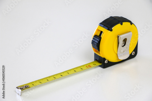 Black and yellow retractable tape measure held in place at 10 cm, on white background, useful tool for measuring length, width and height. Accuracy and precision concept