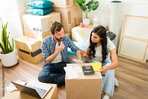 Young couple in their new apartment, sitting amidst cardboard boxes and budgeting for their move