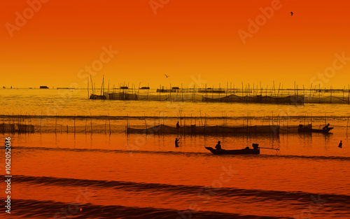 Silhouette of Unknown man catches fish in water. Red sunrise color toning.