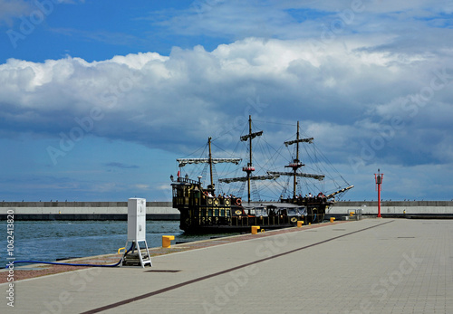 drewniany statek turystyczny ze złotymi dekoracjami, stylizowany piracki statek turystyczny stojący w porcie, wooden tourist ship with golden decorations, golden ancient ship standing in the port 