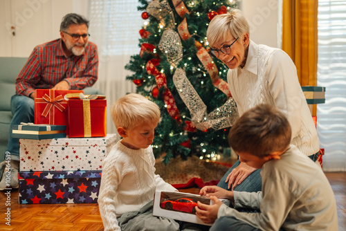 Two brothers opening presents on christmas morning with family