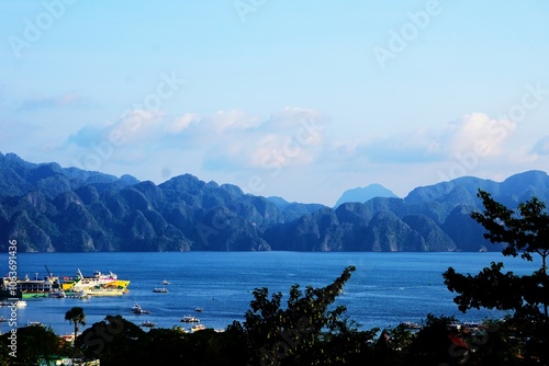 Przepiękna panorama na Palawan. Wysokie góry w tle, na pierwszym planie ocean i statki. Widok na góry, ocean i tropikalną naturę. Panorama na Coron na Filipinach. Turystyka na Filipinach.