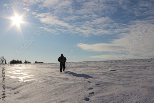 The figure of a man walks through the winter desert, a man walks upward through the snow