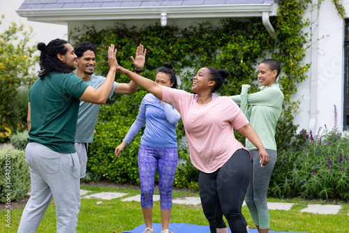 High-fiving outdoors, multiracial friends celebrating fitness and friendship together in park