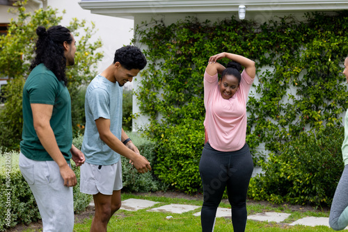 multiracial friends exercising together outdoors, enjoying fitness and laughter in garden