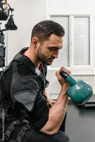 Sportsman in special suit using electrical impulses to stimulate his arms muscles, Exercise progression: Electro stimulator used by man at gym, great for workout inspiration