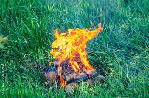 Sport sneakers in bright orange flames, blazing fire on grass creating a powerful visual effect